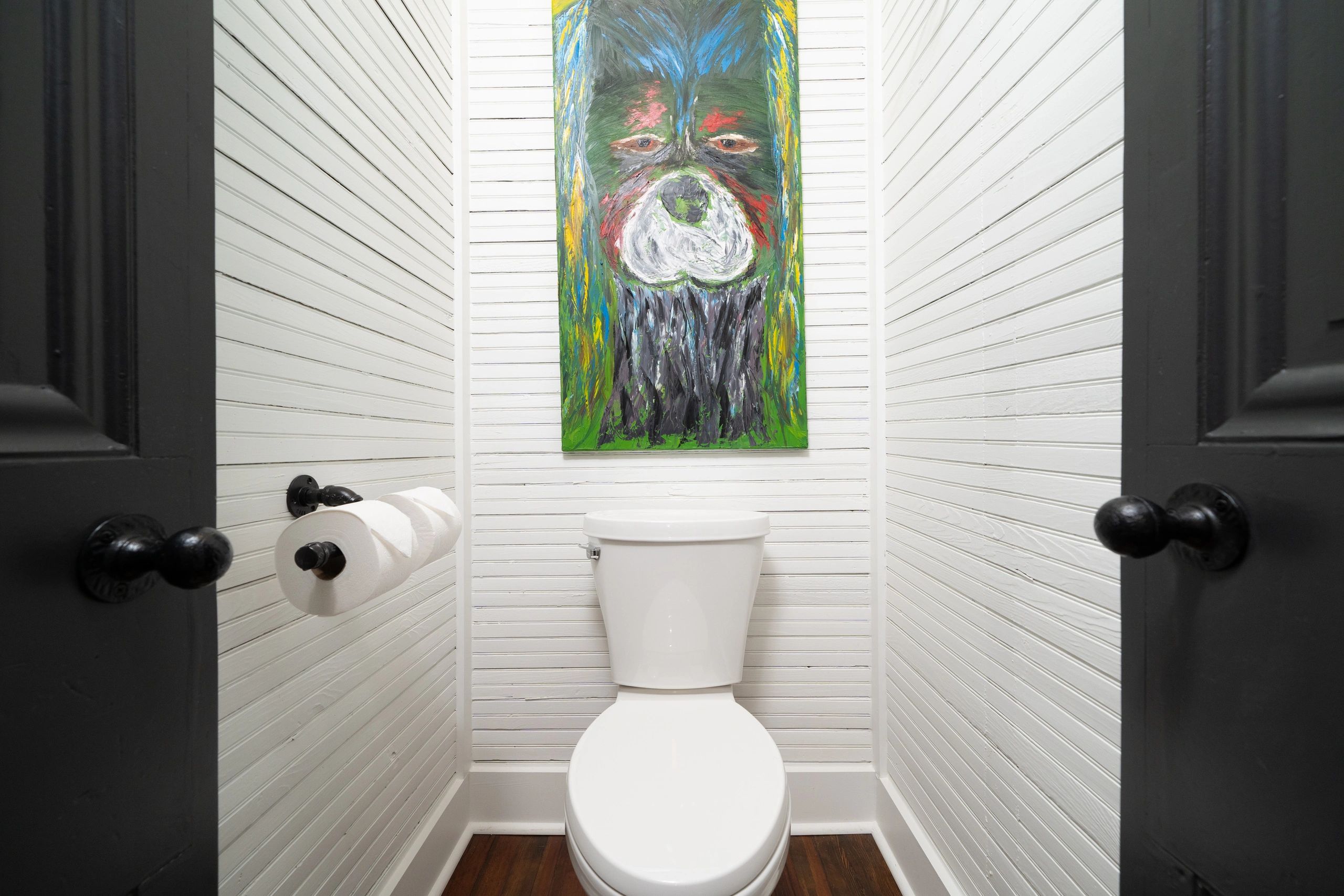Small modern bathroom with a toilet and colorful abstract art above it